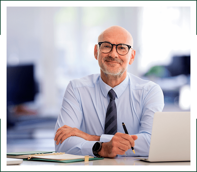 Smiling businessman at desk with laptop