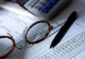Calculator, glasses, and pen on financial documents.